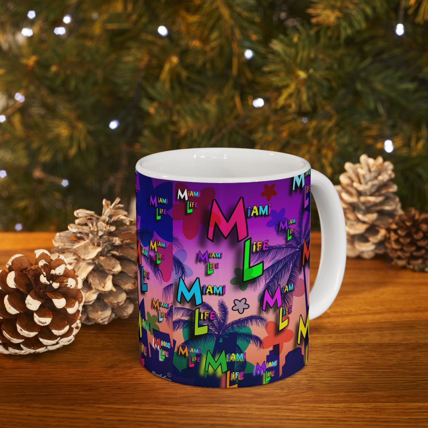 Colorful mug with 'Miami Life' design on a wooden surface with decorative pinecones and a Christmas tree.