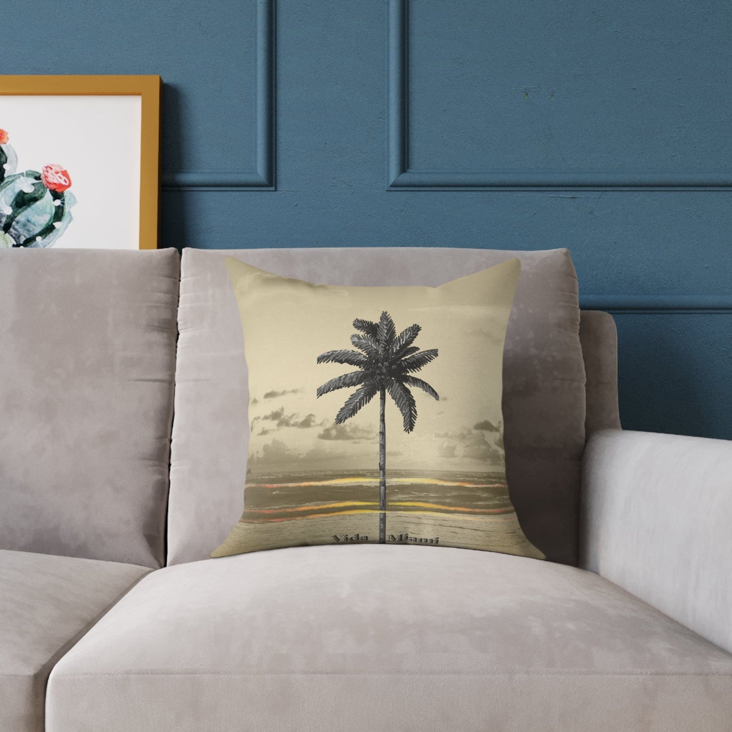Decorative pillow with palm tree design on a gray sofa against a blue wall.
