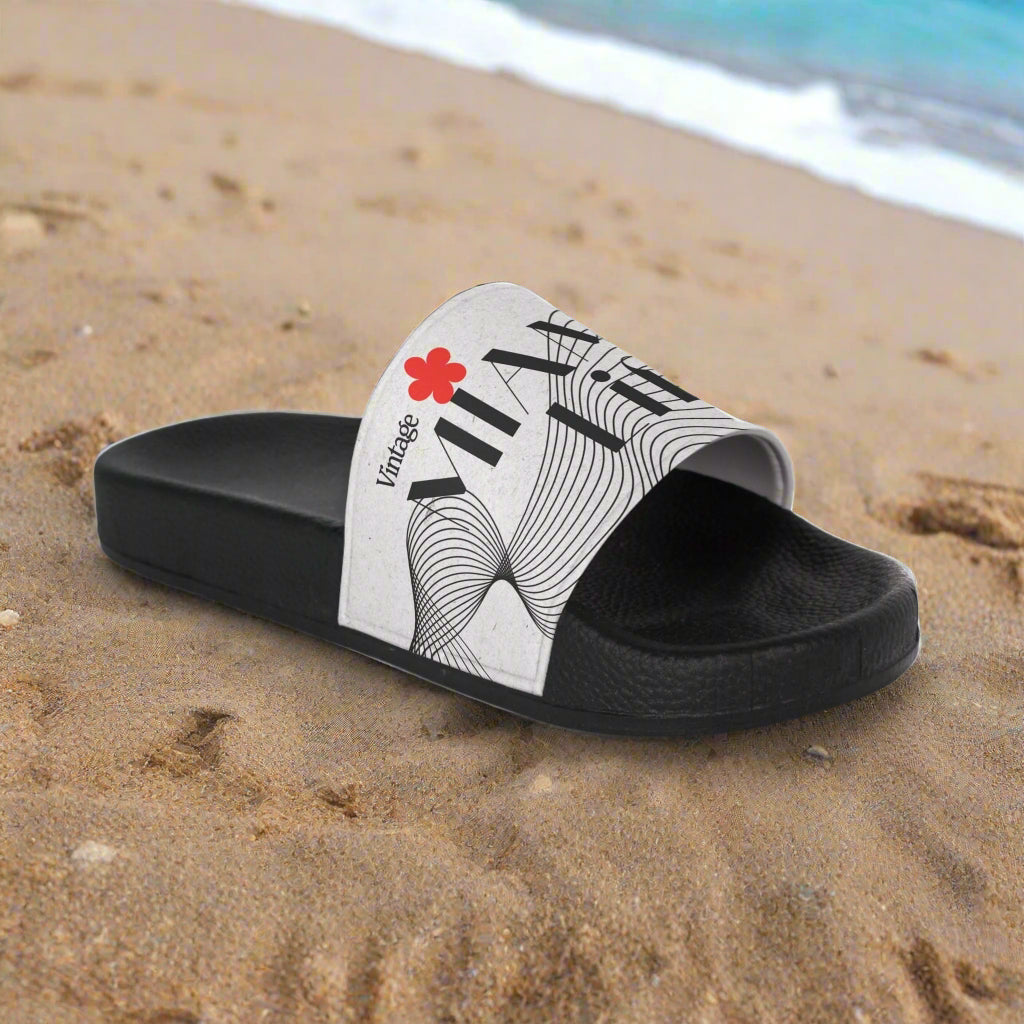 Black slide sandal with white strap featuring black text and a red flower on a white background