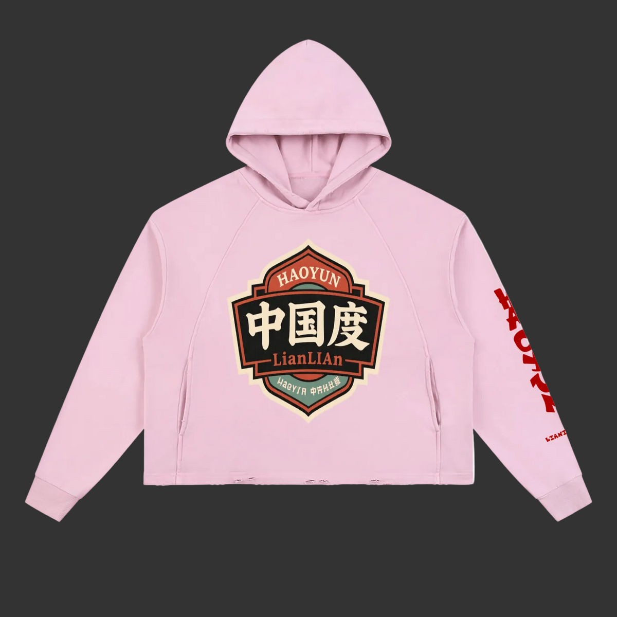 A light pink cropped hoodie with a large graphic on the chest and red text down one sleeve, shown on a plain white background.