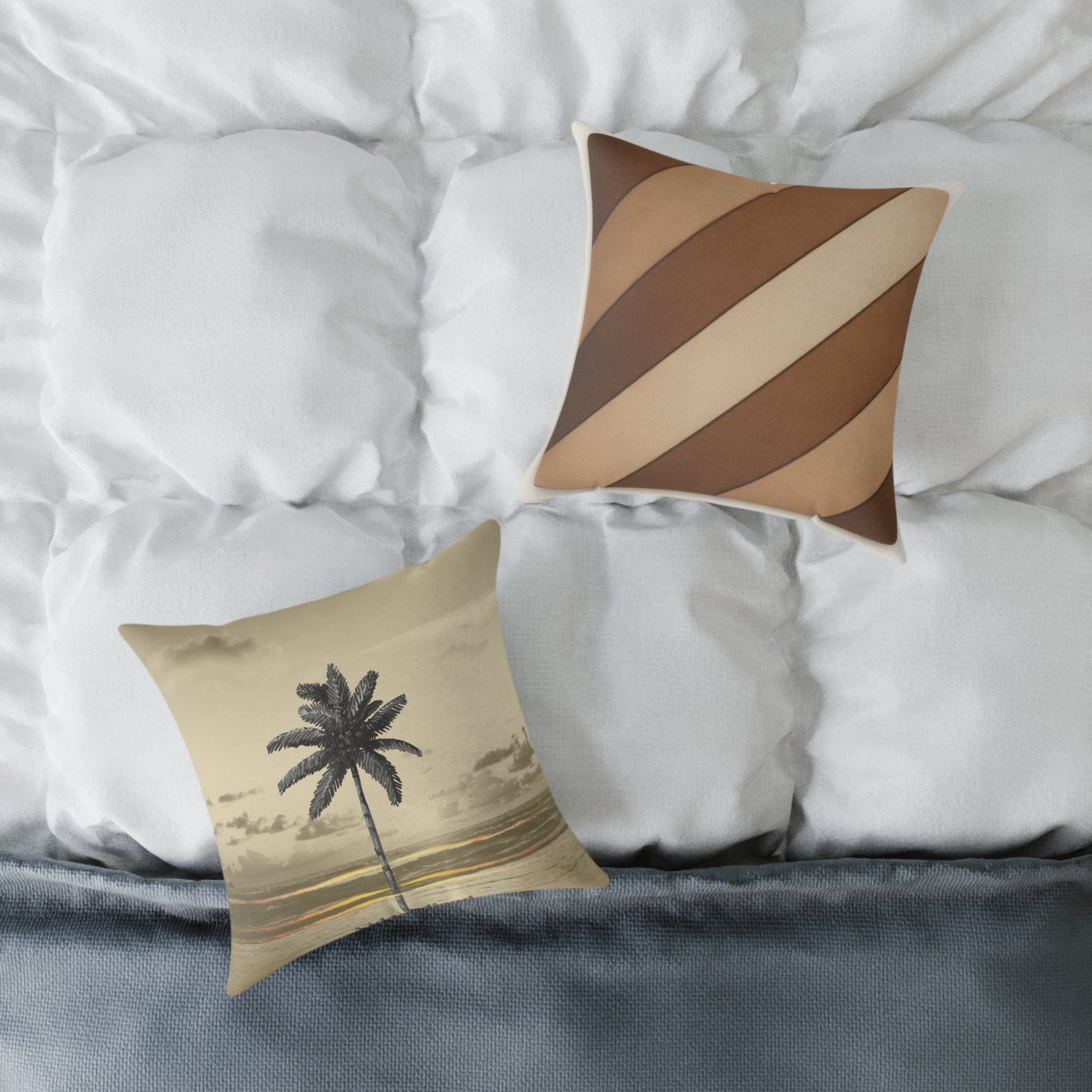 Two decorative pillows on a bed with a palm tree design and striped pattern.
